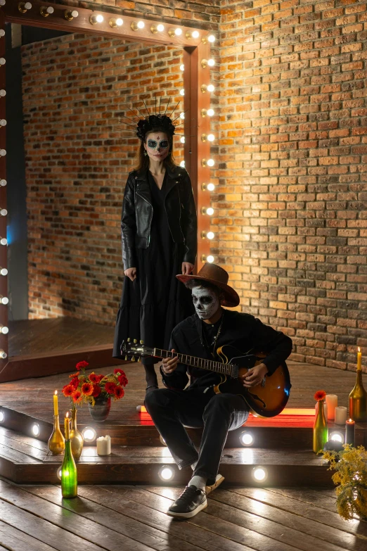 a man sitting on top of a wooden floor next to a woman, an album cover, pexels contest winner, international gothic, celebrating day of the dead, standing in a cantina, guitarists, vantablack wall