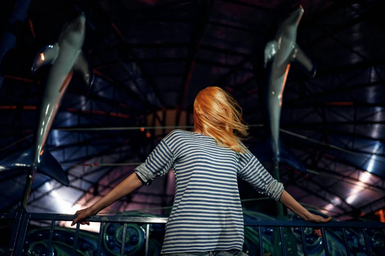 a woman standing on top of a metal railing, inspired by Elsa Bleda, pexels contest winner, kinetic art, a sharknado, fairground rides, striped, young redhead girl in motion