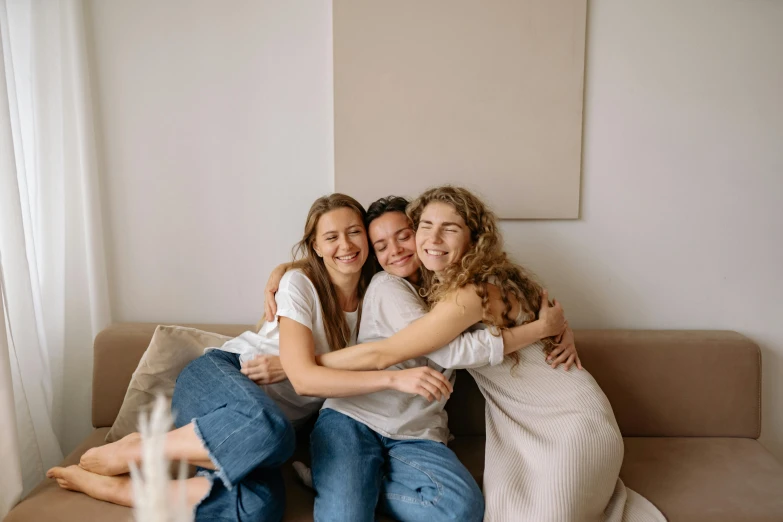 a couple of women sitting on top of a couch, pexels contest winner, three women, hugging each other, avatar image, nursing