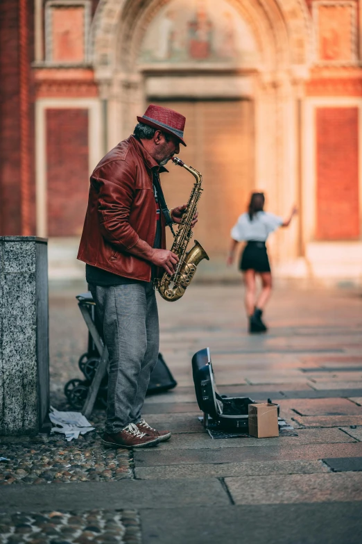 a man in a red jacket playing a saxophone, pexels contest winner, standing on street corner, 🚿🗝📝, brass woman, outside on the ground