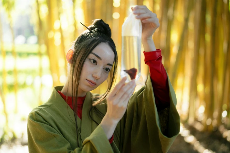 a woman in a green kimono holding a bottle, inspired by Miyagawa Shunsui, pexels contest winner, made of bamboo, avatar image, professional cosplay, film still promotional image