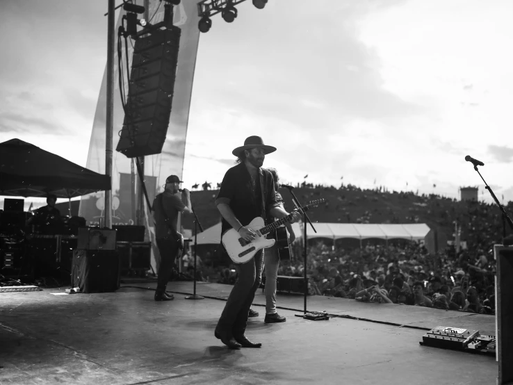 a man that is playing a guitar on a stage, a black and white photo, cowboy on the range, instagram post, standing on the water ground, greg rutkowski and j.dickenson