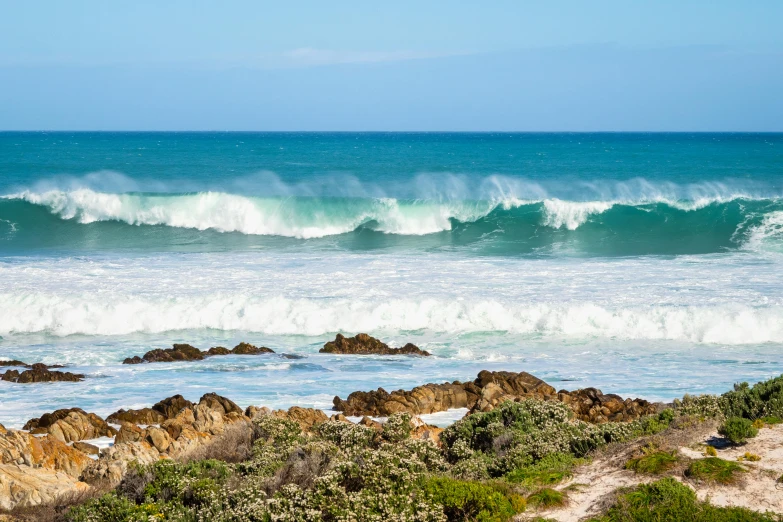 a man riding a surfboard on top of a wave, pexels contest winner, south african coast, rocky seashore, vibrant foliage, whealan