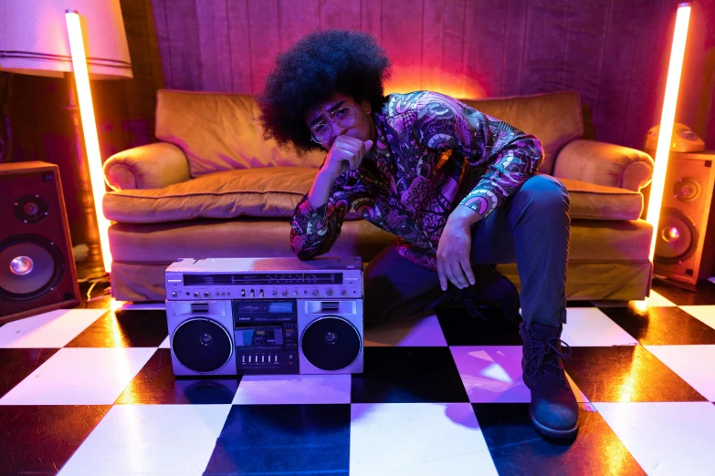 a man sitting on a checkered floor next to a boombox, with afro, purple scene lighting, shot on alexa, indoor scene