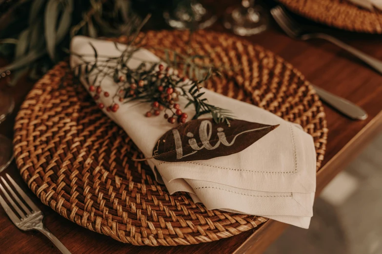 a close up of a place setting on a table, style lettering, leaf, brown, wicker art