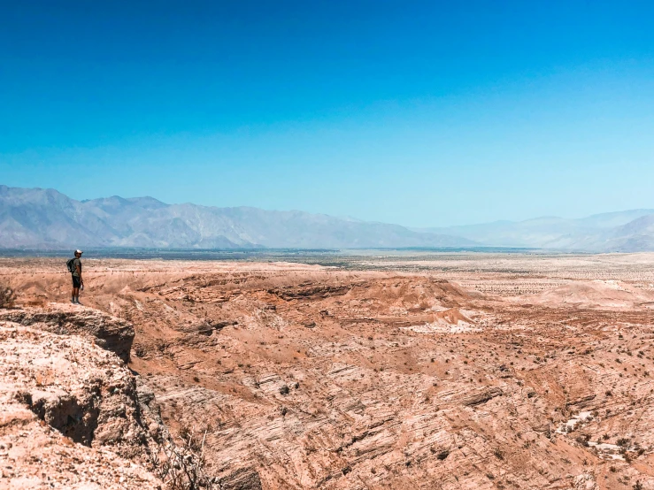 a man standing on top of a cliff in the desert, by Julia Pishtar, pexels contest winner, chile, panorama view, photo from the dig site, palm springs