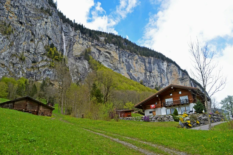 a couple of cabins sitting on top of a lush green hillside, by Caroline Mytinger, pexels contest winner, les nabis, lauterbrunnen valley, avatar image, natural cave wall, youtube thumbnail