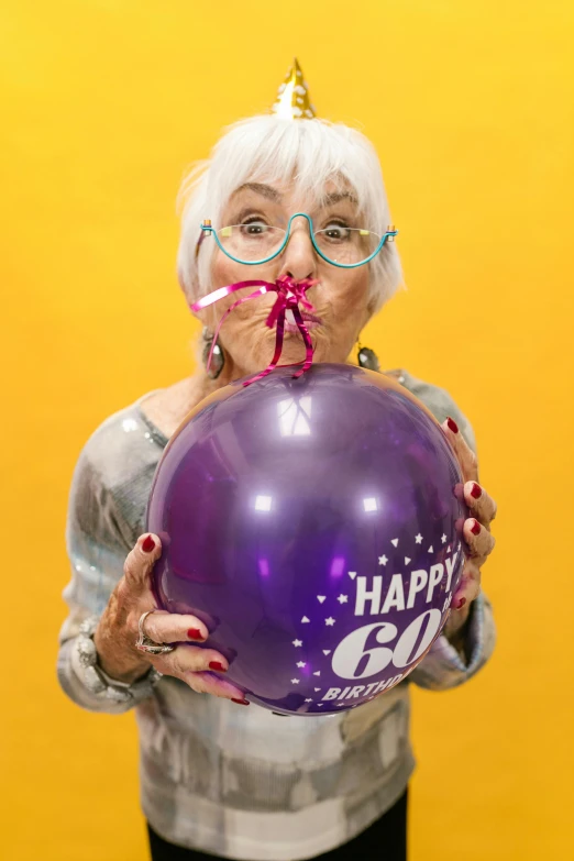 a woman holding a purple balloon in front of her face, he is about 6 0 years old, tongue out, 60mm, and