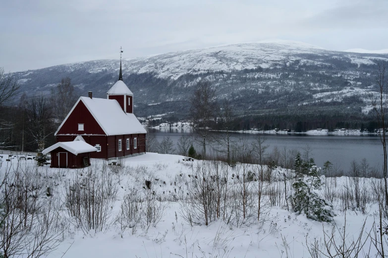 a red church sitting in the middle of a snow covered field, inspired by Eero Järnefelt, pexels contest winner, mountains and lakes, grey, rustic, 1940s photo