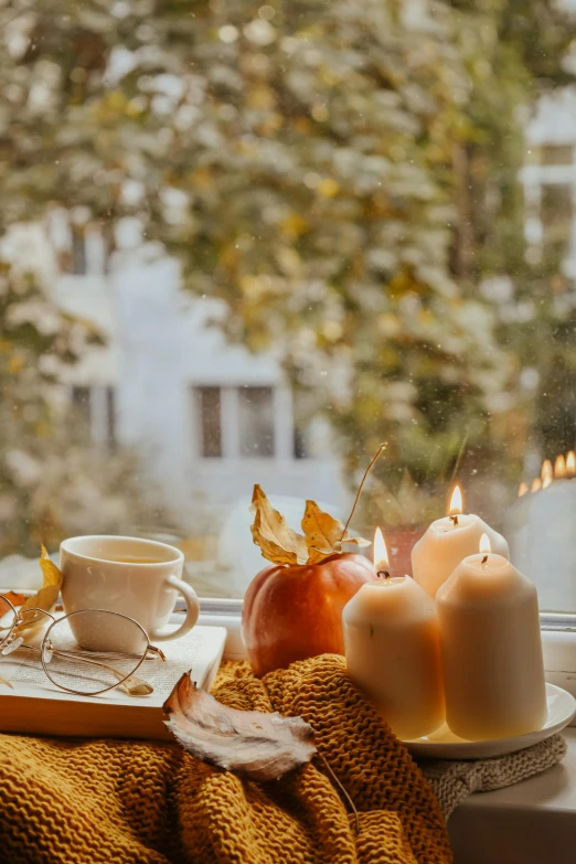 a cup of coffee sitting on top of a window sill, a still life, by Niko Henrichon, trending on pexels, romanticism, glowing candles, in fall, square, college