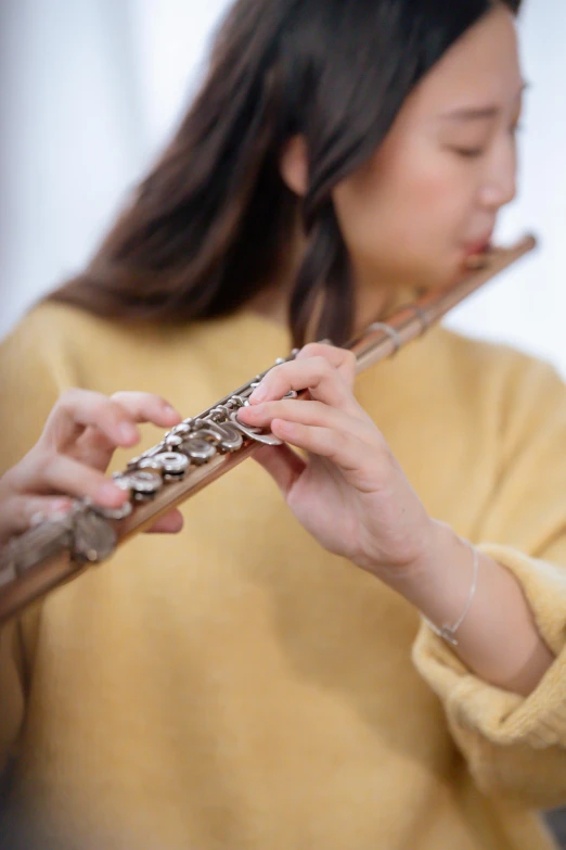 a woman in a yellow sweater playing a flute, an album cover, inspired by Zheng Xie, trending on pexels, photorealism, low detail, 🚿🗝📝