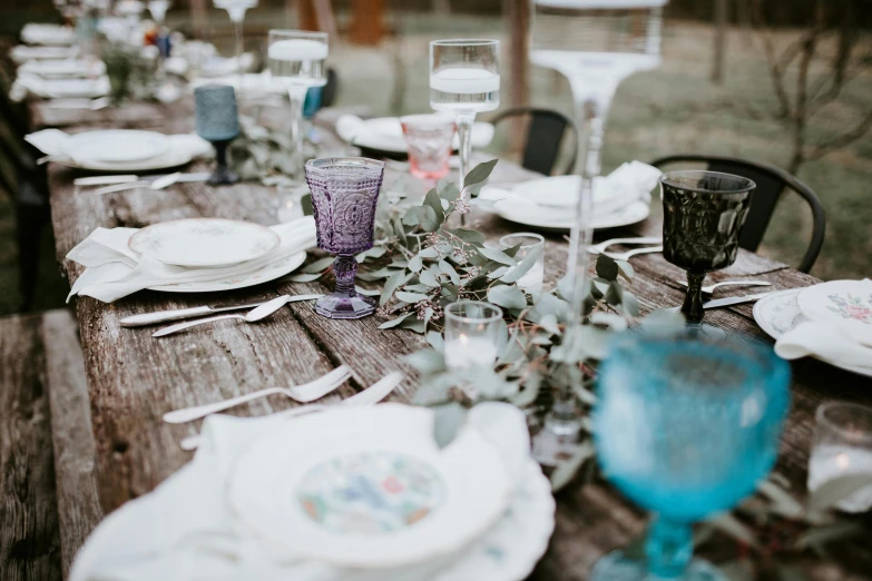 a wooden table topped with plates and glasses, unsplash, vines and blue foliage, vintage photo, background image, long table