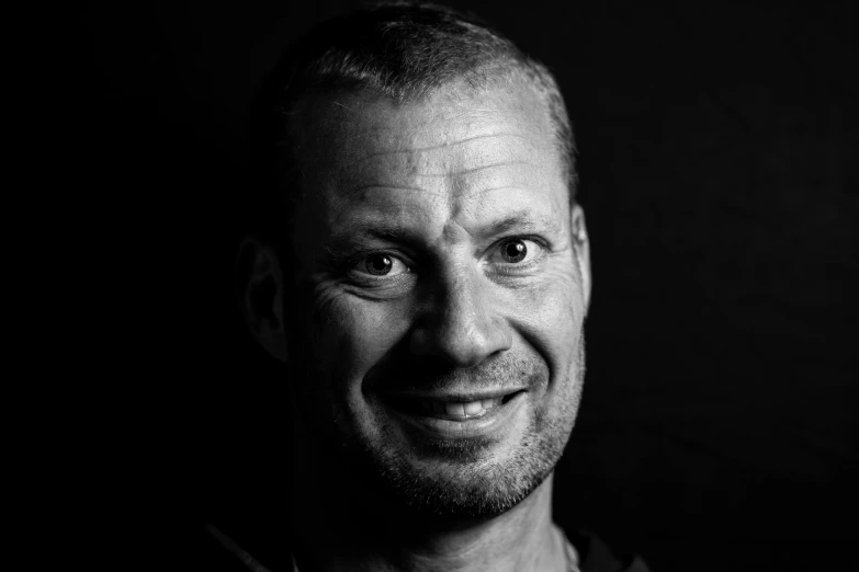 a black and white photo of a man smiling, a black and white photo, by Salomon van Abbé, phil spencer, mark van haitsma, portrait top light, full colour