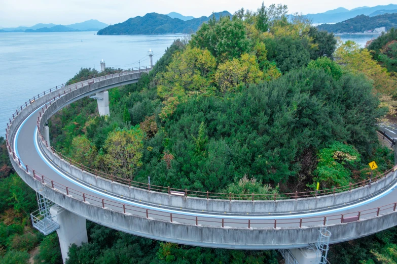 a bridge over a large body of water, inspired by Tadao Ando, unsplash, monorail, hilly road, covered with vegetation, nagasaki