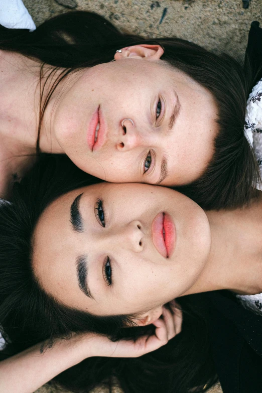 a couple of women laying on top of each other, inspired by Wang Duo, trending on pexels, realism, perfect face symmetry, oriental face, lesbian, delicate eyebrows