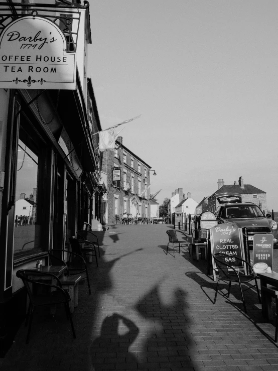 a black and white photo of a coffee shop, by Kev Walker, sunlight and whimsical houses, walking to the right, the sun is shining. photographic, small town