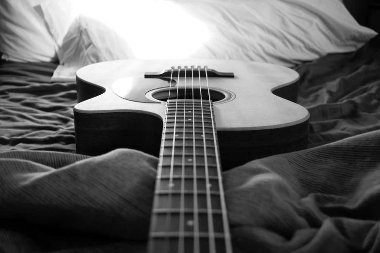 a black and white photo of a guitar on a bed, by Felix-Kelly