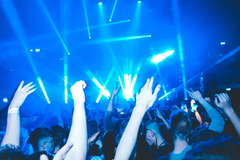 a crowd of people at a concert with their hands in the air, pexels contest winner, happening, blue neon lighting, photograph of three ravers, holding a blue lightsaber, dancefloor kismet