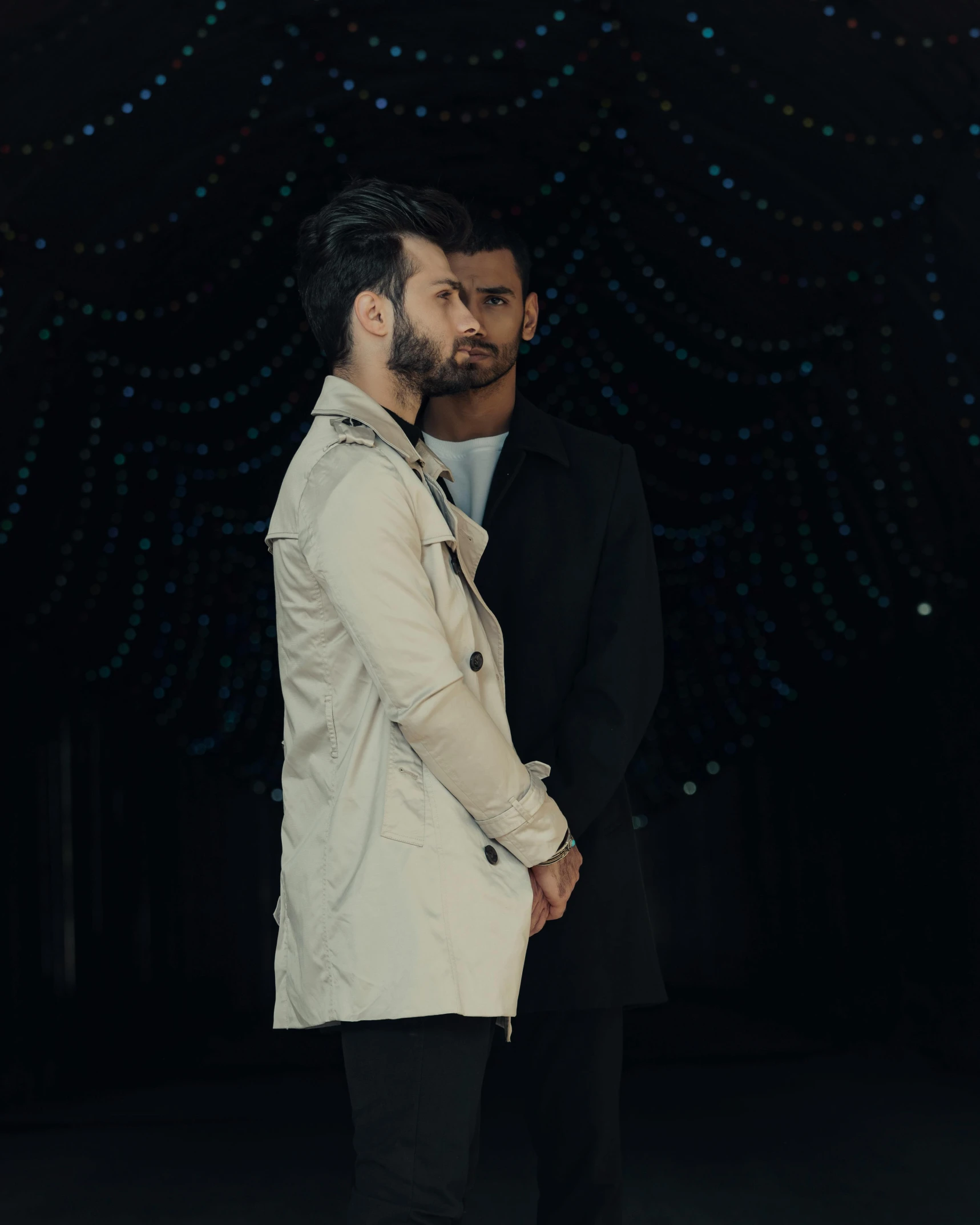 two men standing next to each other in a dark room, an album cover, unsplash, romanticism, fashion show photo, assyrian, wearing trenchcoat, lgbt