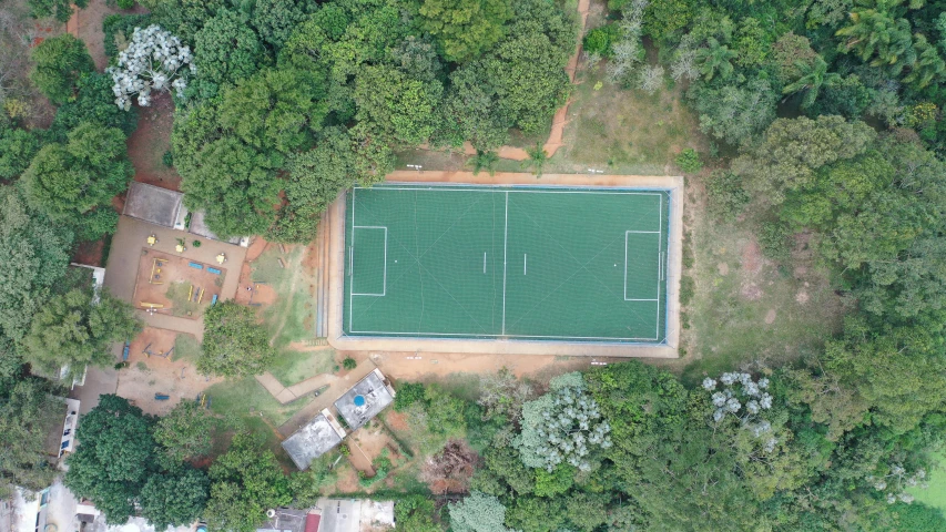an aerial view of a tennis court surrounded by trees, by david rubín, hurufiyya, on a soccer field, sri lankan landscape, let's play, fps view