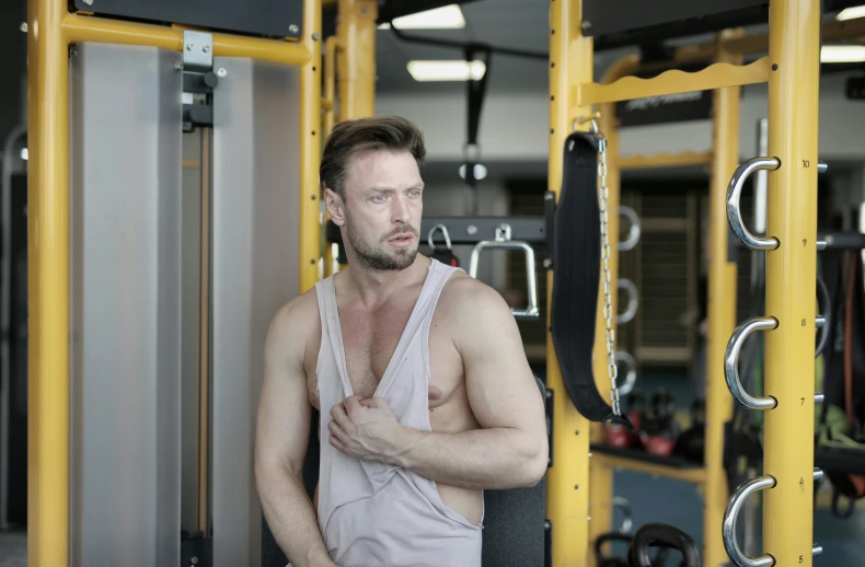 a man standing in front of a machine in a gym, pexels contest winner, open v chest clothes, 30 year old man :: athletic, profile image, marton csokas