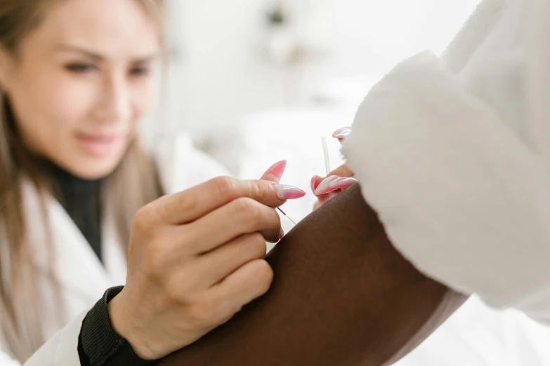 a close up of a person putting something on a person's arm, a photo, holding a syringe, profile image, candy treatments, brown