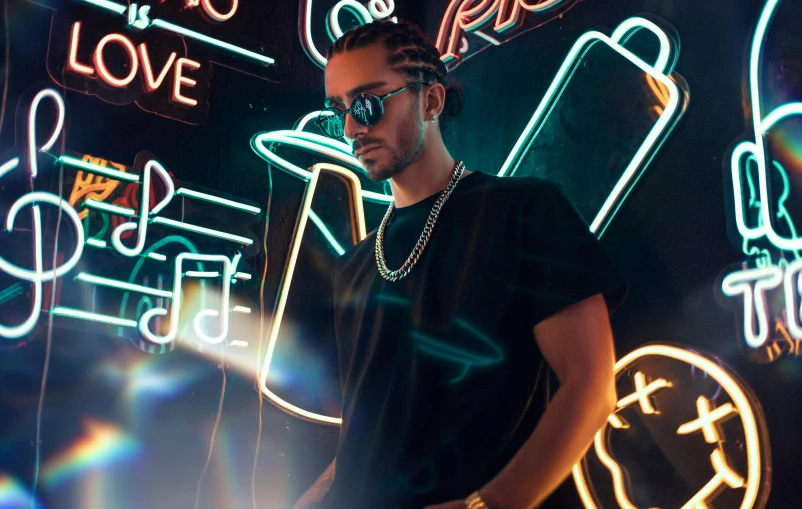 a man standing in front of neon signs, an album cover, by Julia Pishtar, trending on pexels, singer maluma, neck chains, reflecting light in a nightclub, dr zeus