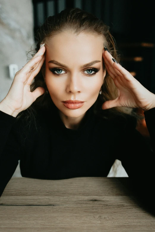 a woman sitting at a table with her hands on her head, a picture, trending on pexels, blue eyes and large forehead, frown fashion model, gif, anna nikonova aka newmilky