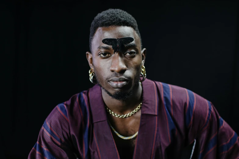 a man with black paint on his face, an album cover, trending on pexels, hyperrealism, hi mark ( akwaaba tommy ), large eyebrows, 2 2 years old, in style of nadine ijewere