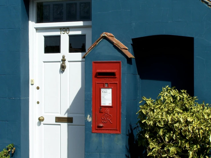 a blue building with a white door and a red post box, inspired by Clarice Beckett, pexels contest winner, private press, a wooden, smokey burnt envelopes, red wall, a small
