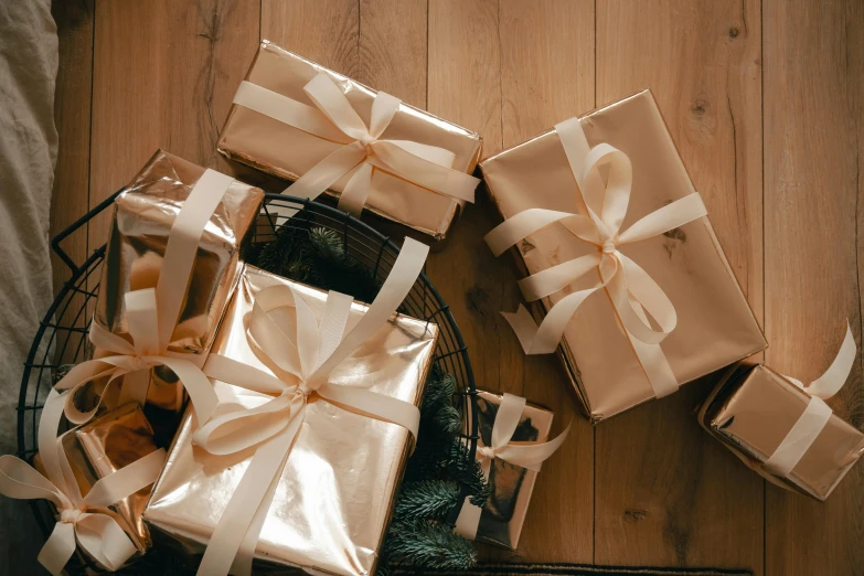 a basket filled with wrapped presents on top of a wooden floor, pexels contest winner, arts and crafts movement, gold foil, beige, bows, thumbnail