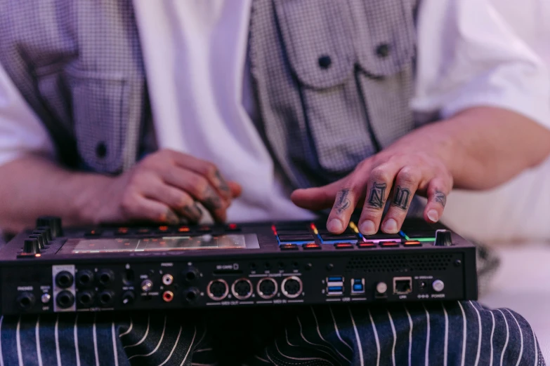 a close up of a person using a dj controller, an album cover, by Joe Bowler, unsplash, tattooed, moog modular synthesizer, musicians playing instruments, sitting down