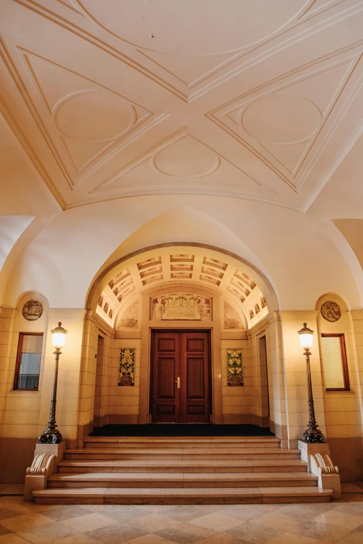 the entrance to a building with a red door, inspired by Sydney Prior Hall, art nouveau, complex ceiling, royal palace interior, front lighting, arched ceiling