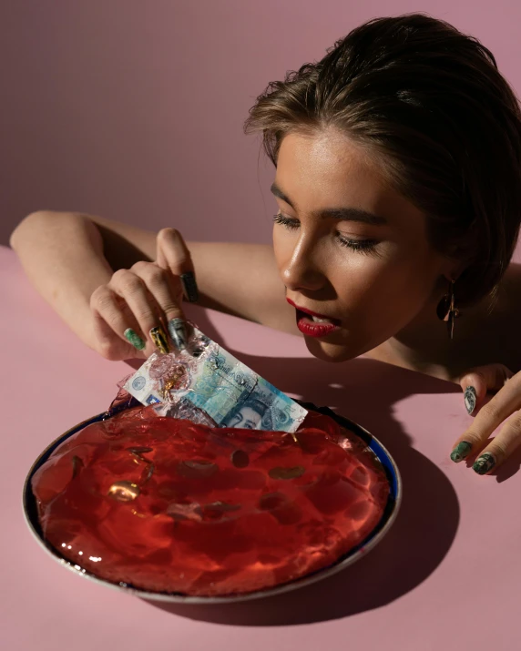 a woman sitting at a table with a plate of food, an album cover, inspired by Tracey Emin, trending on tumblr, magic realism, banknotes flying from barrel, colourful slime, photoshoot for skincare brand, in a red dish