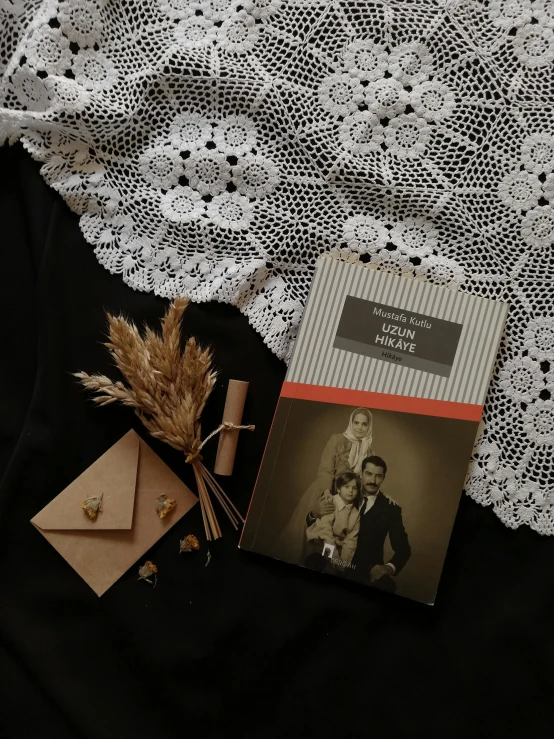 a book sitting on top of a table next to a flower, a black and white photo, inspired by irakli nadar, with victorian clothing, black and auburn colour pallet, family photo, flatlay
