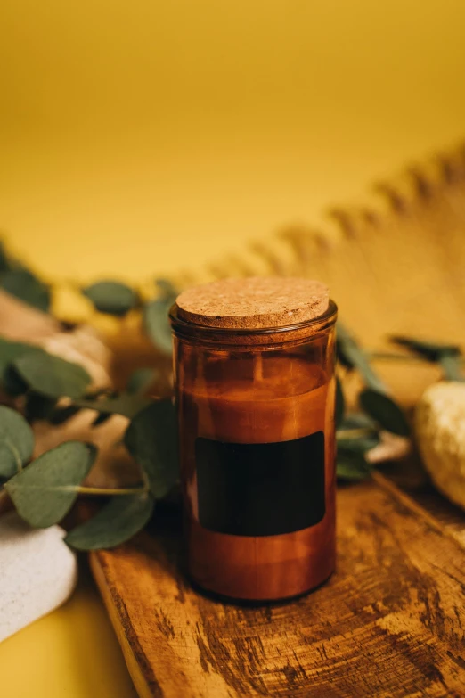 a candle sitting on top of a wooden cutting board, a picture, unsplash, relaxed. gold background, apothecary, full body image, eucalyptus