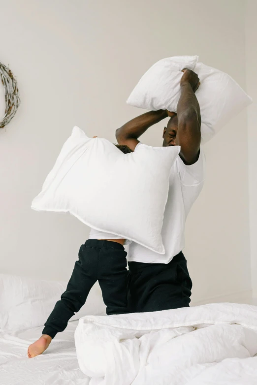 a man holding a pillow on top of a bed, black man, all white, 10k, throw