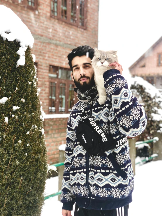 a man standing in the snow holding a cat, a picture, trending on reddit, drake the rapper wearing a kurta, outlive streetwear collection, wearing casual sweater, traditional romanian clothing