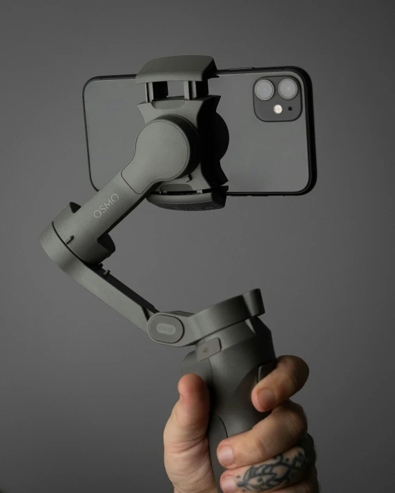 a close up of a person holding a cell phone, extended robotic arms, textured base ; product photos, dark grey, lut