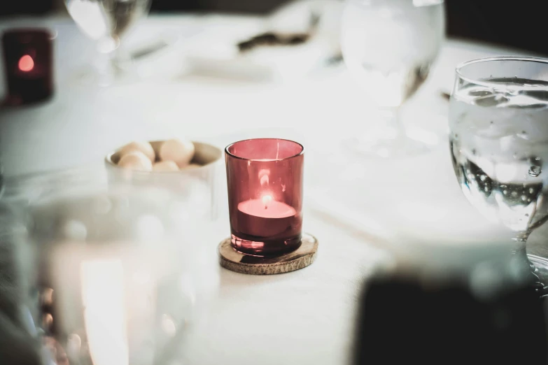 a red candle sitting on top of a white table, pexels, pink, family dinner, instagram picture, linen