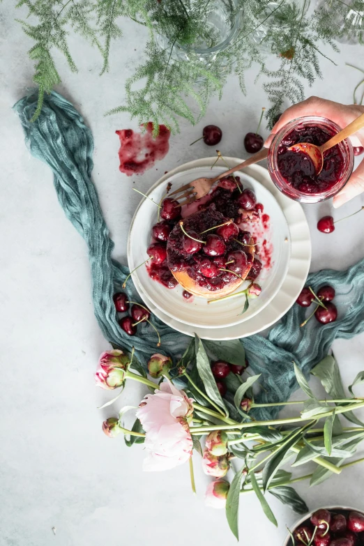 a person holding a glass of wine next to a bowl of cherries, inspired by Henriette Grindat, unsplash contest winner, draped in velvet and flowers, on a white table, bun ), swedish