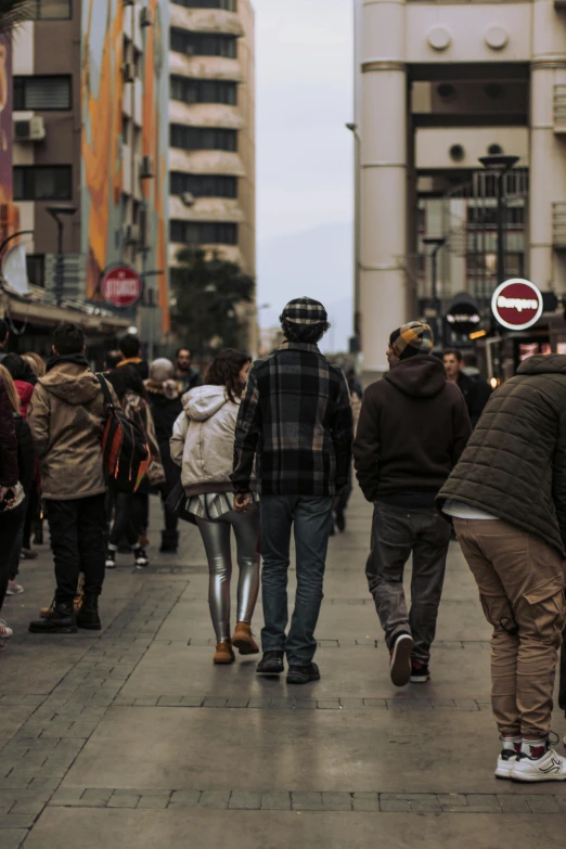 a group of people walking down a street next to tall buildings, by Niko Henrichon, trending on unsplash, happening, chile, teenage boy, human heads everywhere, madrid