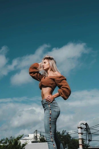 a woman standing on top of a skateboard ramp, trending on pexels, wearing a sexy cropped top, tall fluffy clouds, brown sweater, 5 0 0 px models