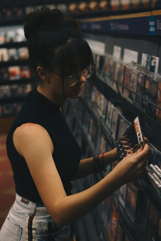 a woman looking at a video game in a store, an album cover, by Everett Warner, pexels contest winner, girl with glasses, [ cinematic, inspect in inventory image, half asian