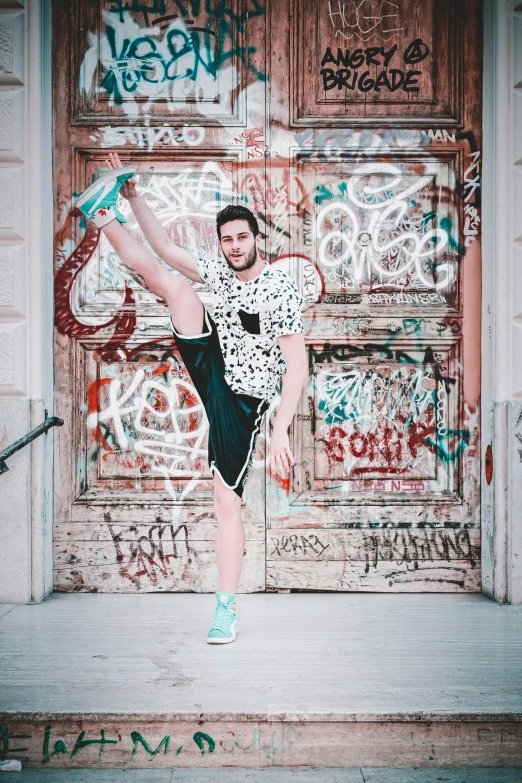 a woman standing on one leg in front of a door, inspired by Ludovit Fulla, pexels contest winner, graffiti, handsome man, wearing adidas clothing, patterned clothing, sam nassour