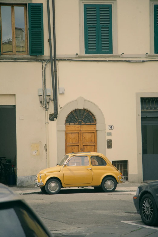 a yellow car is parked in front of a building, pexels contest winner, renaissance, vsco film grain, florence, low quality photo, a quaint