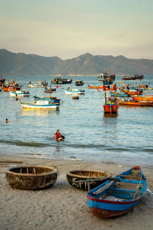 a group of boats sitting on top of a sandy beach, inspired by Steve McCurry, vietnamese woman, fish flocks, calm evening, bowl