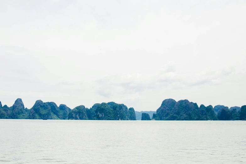 a large body of water with mountains in the background, by Rachel Reckitt, pexels contest winner, ao dai, two medium sized islands, overexposed photograph, limestone