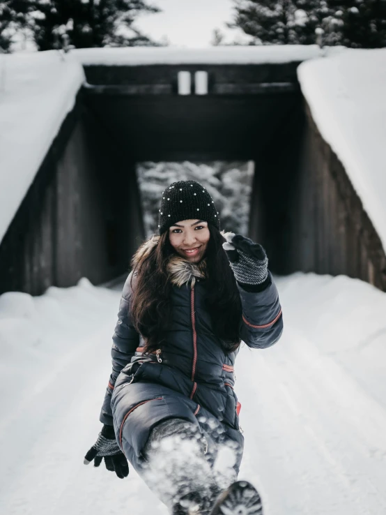 a woman riding a snowboard down a snow covered slope, by Julia Pishtar, pexels contest winner, sitting under bridge, in a cabin, lovingly looking at camera, jovana rikalo