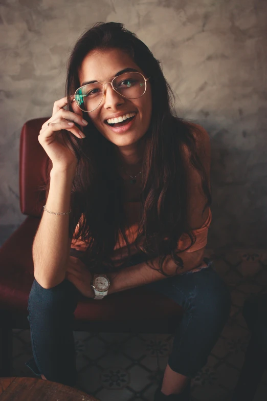 a woman sitting on a red chair talking on a cell phone, trending on pexels, renaissance, square rimmed glasses, young woman with long dark hair, laughingstock, an olive skinned